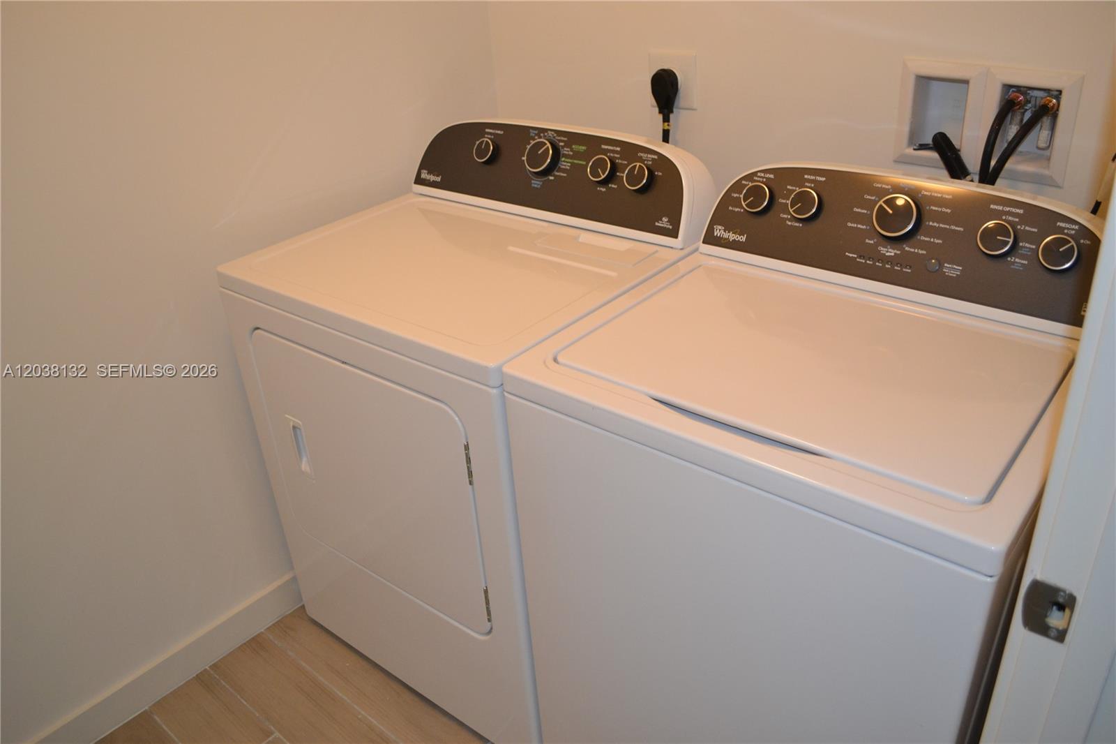 A laundry room features a white Whirlpool washer and dryer set against a plain wall — 999 SW 1st Ave # 3202, Miami FL 33130, MIAMI, FL