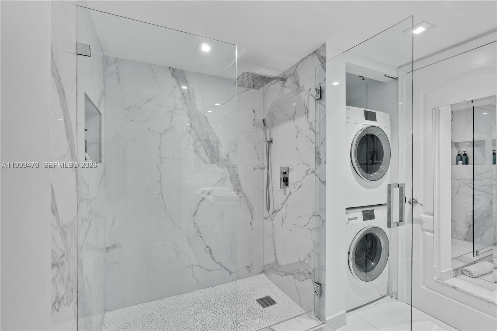 A bathroom features a glass-enclosed marble shower next to a stacked washer and dryer — 1200 Brickell Bay Dr # 2017, Miami FL 33131, MIAMI, FL