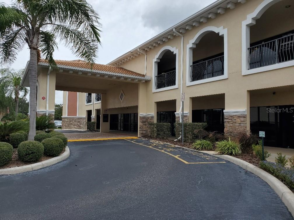 The exterior of a multi-story commercial building features a covered drop-off area and arched balconies — 2984 ALAFAYA TRAIL, OVIEDO, FL