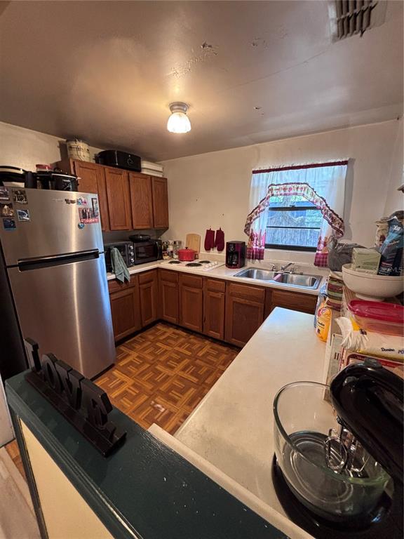 A kitchen features wood cabinets, a stainless steel refrigerator, a double sink, and patterned flooring — 3137 NW 6TH STREET, GAINESVILLE, FL