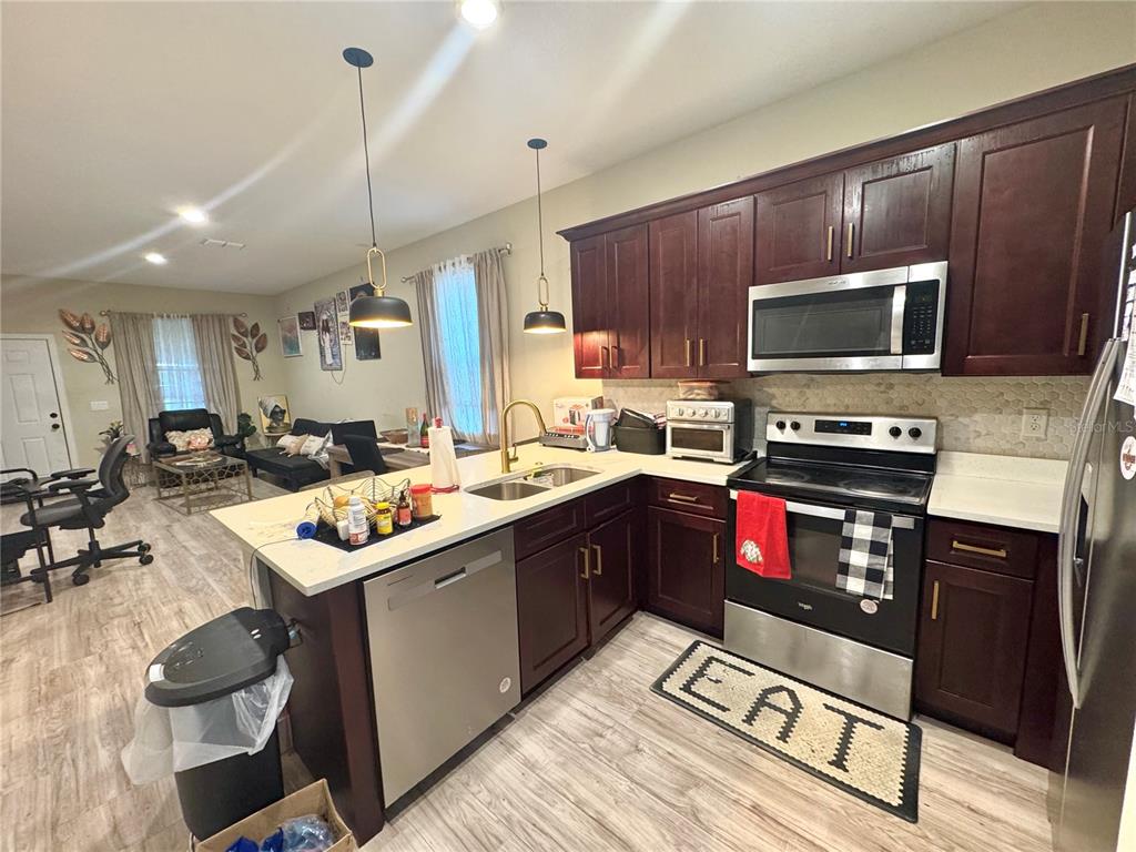 A kitchen with dark wood cabinets, stainless steel appliances, and an island with a sink — 113 E CLEVELAND STREET, APOPKA, FL