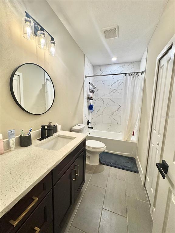A bathroom features a dark vanity with a light countertop, a round mirror, and a tub-shower — 113 E CLEVELAND STREET, APOPKA, FL