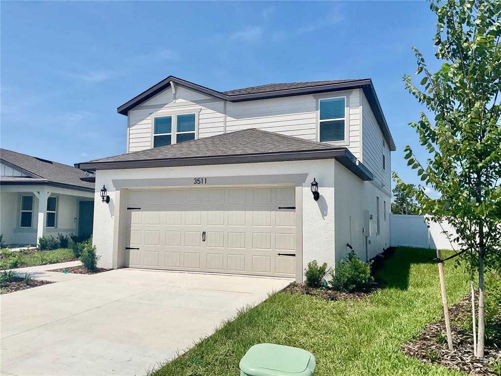 A two-story house with a beige garage door and white stucco exterior under a blue sky — 3511 HORNBEAM ROAD, SPRING HILL, FL