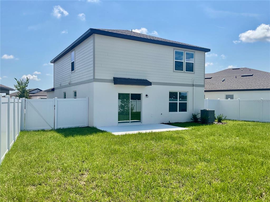 The exterior rear view of a two-story house features white siding, stucco, and a patio — 3511 HORNBEAM ROAD, SPRING HILL, FL