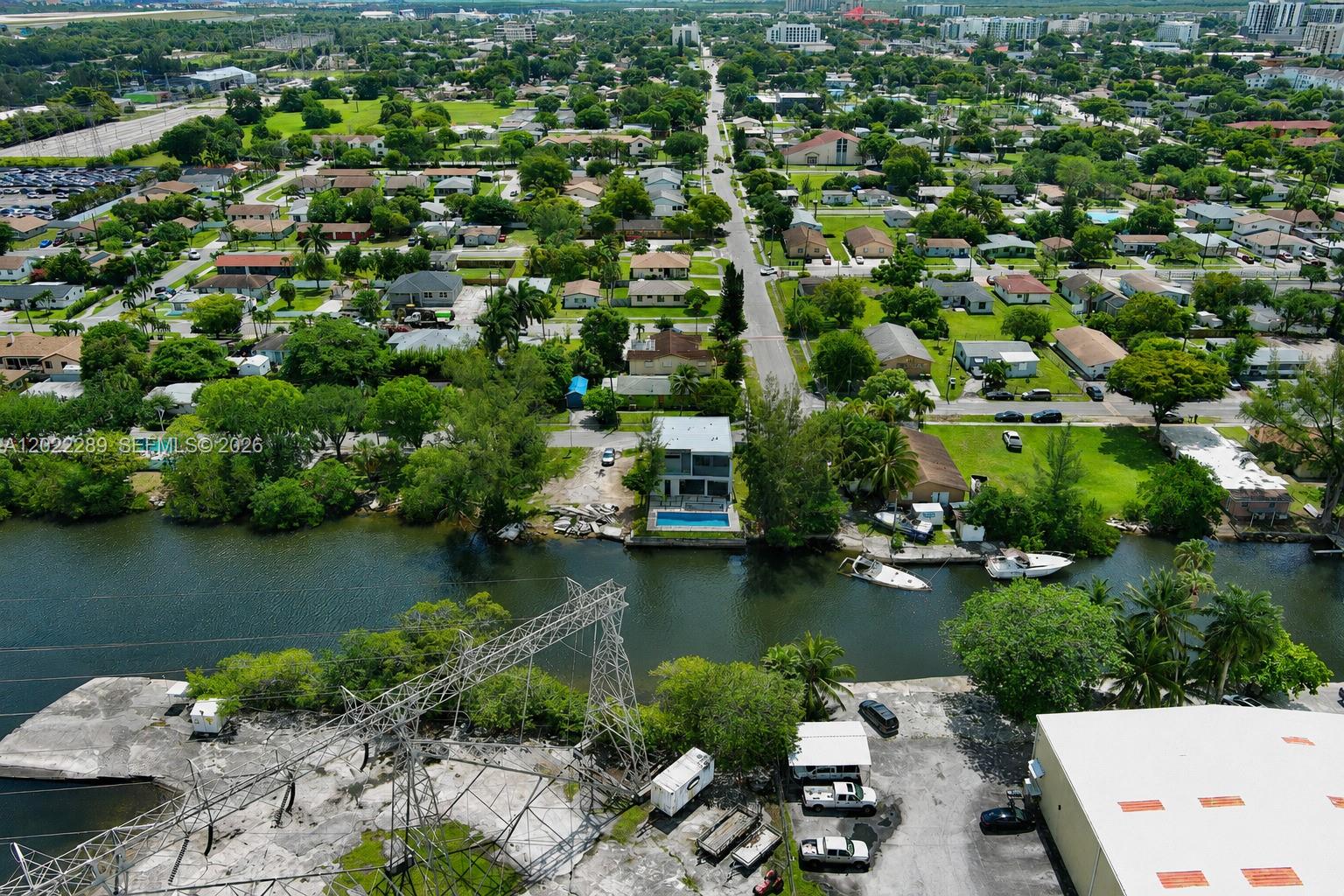 An aerial view shows a waterfront house with a pool situated near a power line tower — 201 NW 14 WAY, Dania Beach FL 33004, DANIA BEACH, FL