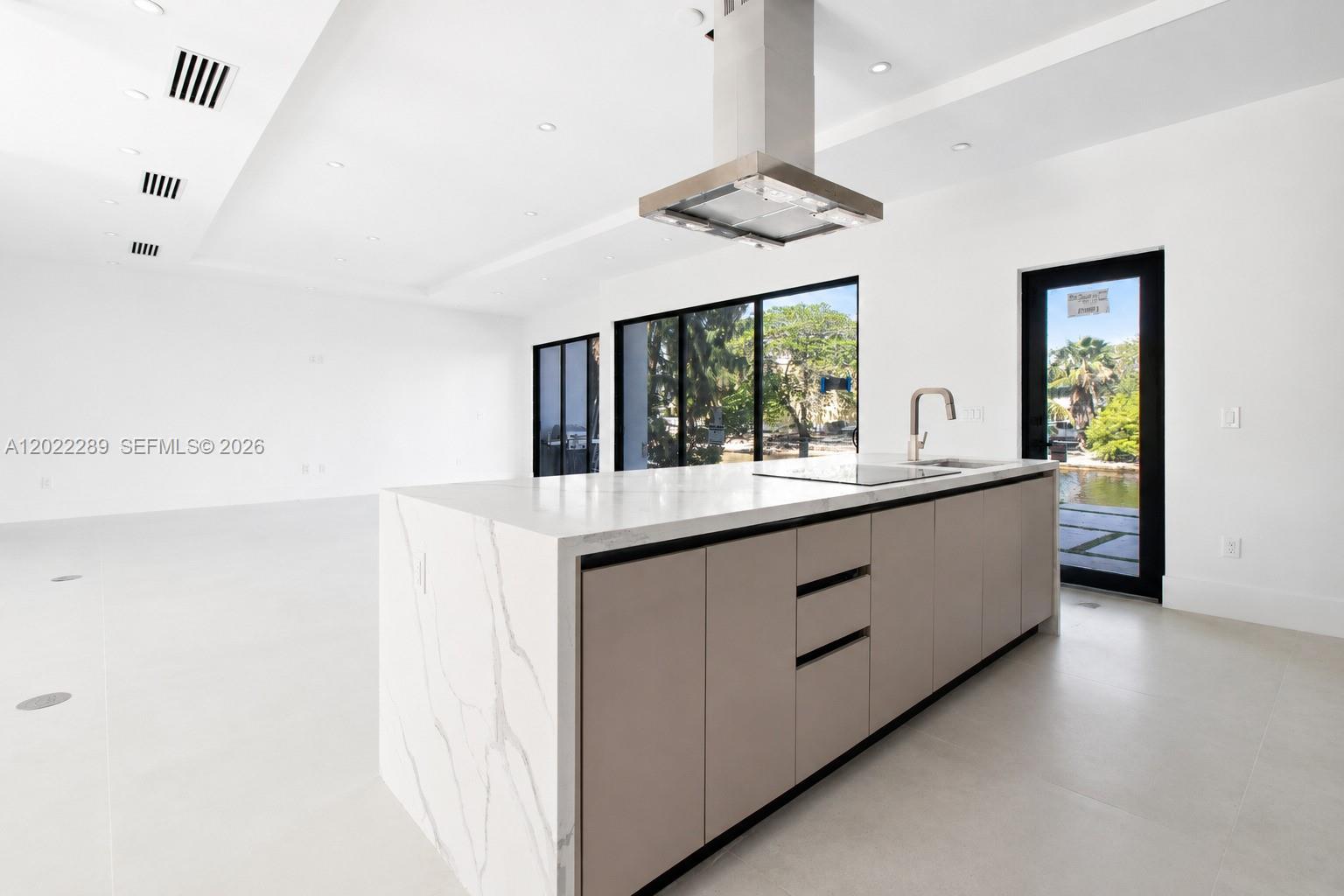 A modern kitchen features a marble-topped island, stainless steel range hood, and floor-to-ceiling windows — 201 NW 14 WAY, Dania Beach FL 33004, DANIA BEACH, FL