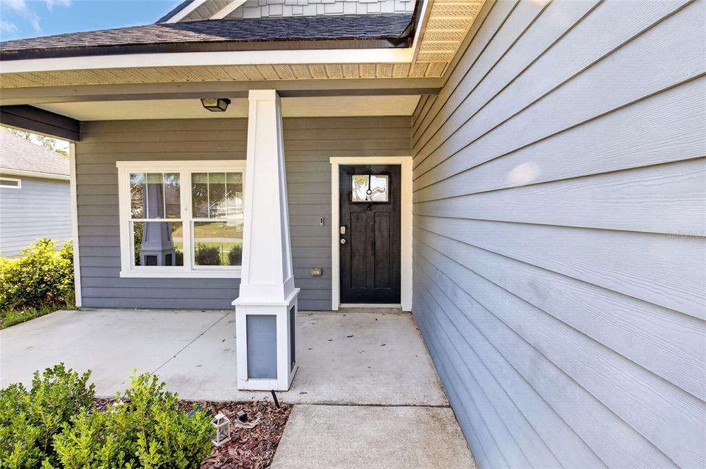 A covered front porch features gray horizontal siding, a white column, and a black door — 16659 NW 192ND TERRACE, HIGH SPRINGS, FL