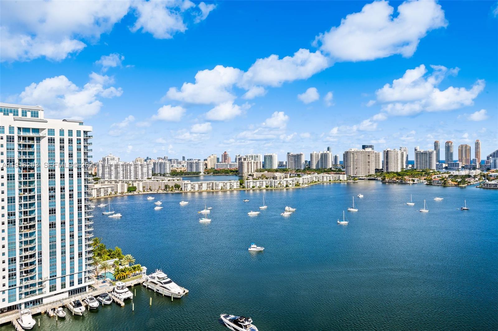 An aerial view of a waterfront high-rise building overlooking a bay filled with boats — 17111 Biscayne Blvd # 2103, North Miami Beach FL 33160, NORTH MIAMI BEACH, FL