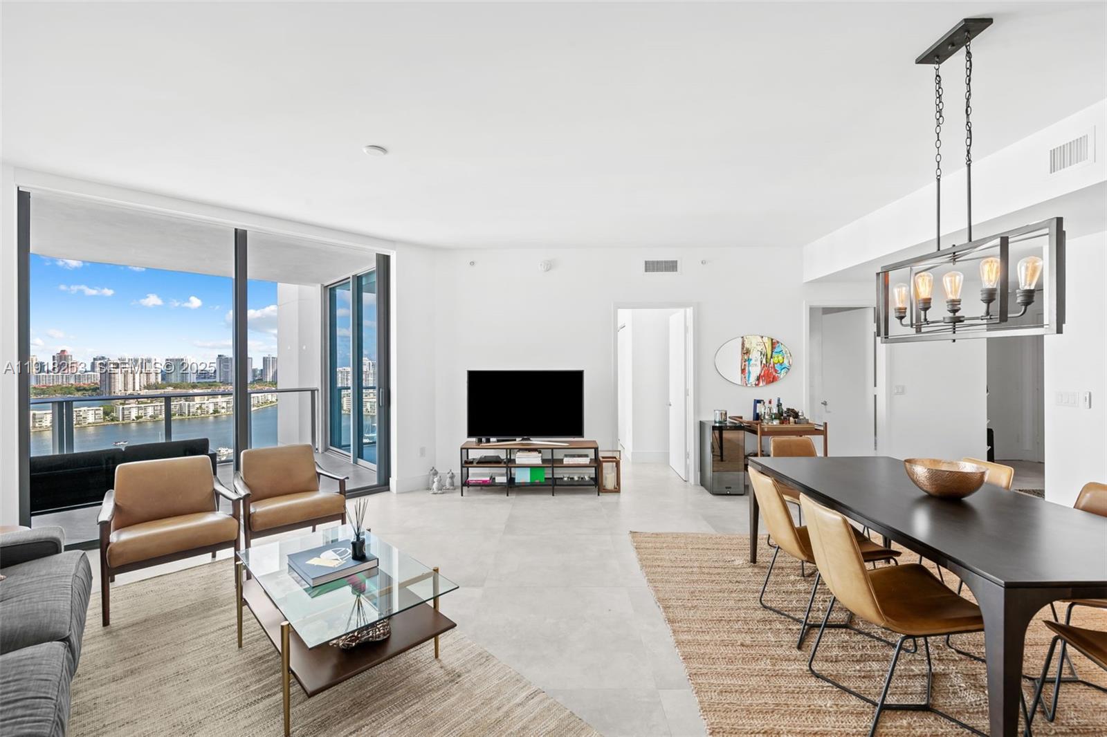 A bright living and dining area features tile floors, a balcony, and a modern chandelier — 17111 Biscayne Blvd # 2103, North Miami Beach FL 33160, NORTH MIAMI BEACH, FL