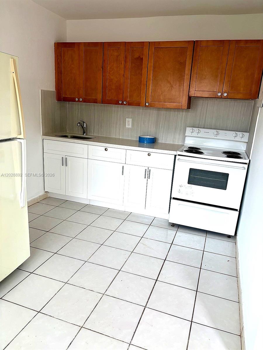 A kitchen features wood upper cabinets, white lower cabinets, a white stove, and tiled flooring — 1629 Taft St # 2, Hollywood FL 33020, HOLLYWOOD, FL