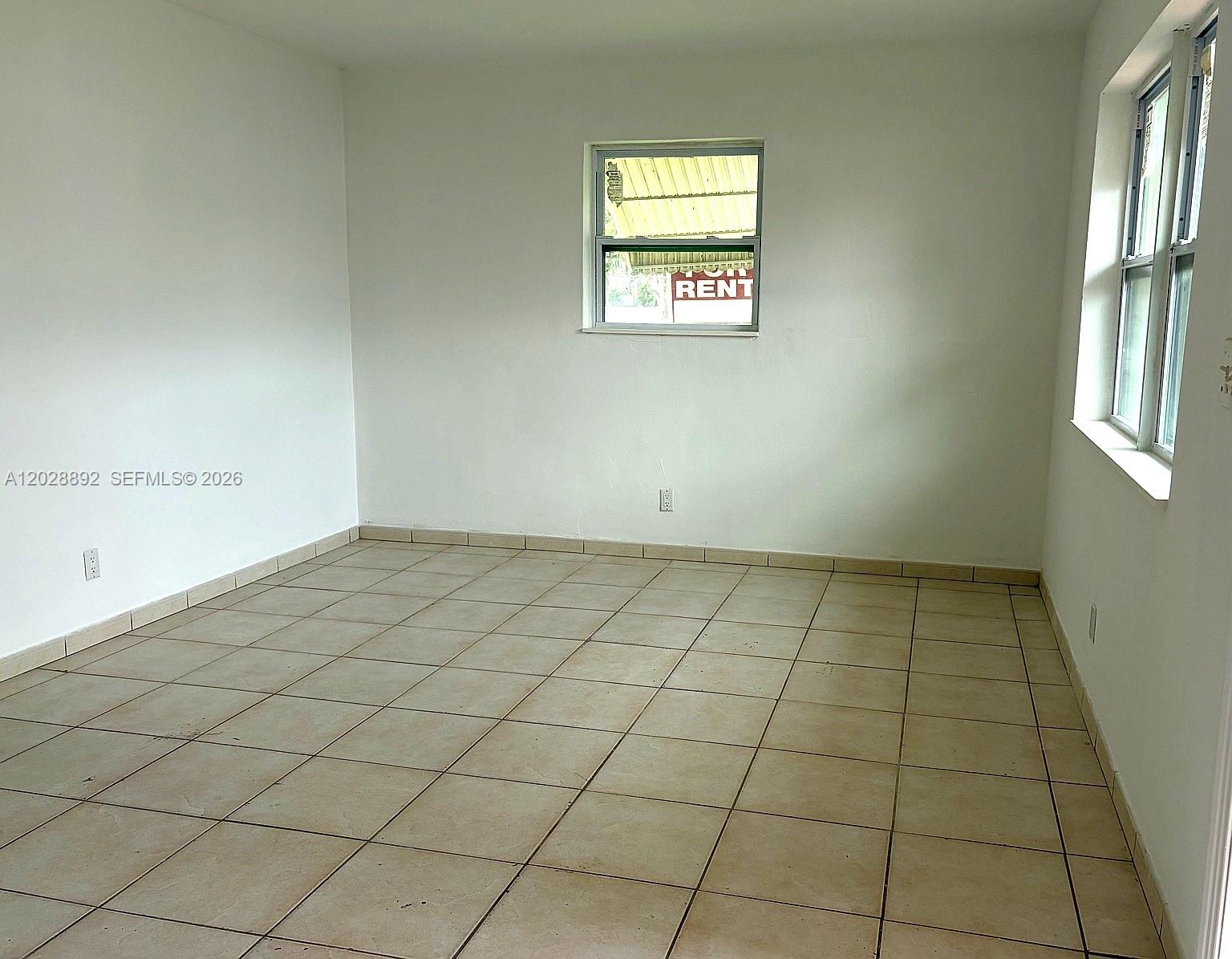 An empty room features white walls, tan tile flooring, and two windows — 1629 Taft St # 2, Hollywood FL 33020, HOLLYWOOD, FL