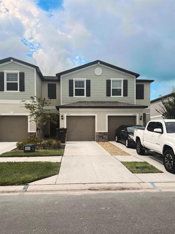 A two-story townhouse exterior features light green siding, brown garage doors, and a concrete driveway — 2541 SUNRAY VENUS WAY, RUSKIN, FL