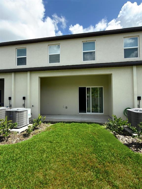 The exterior of a two-story house features a covered patio, sliding glass doors, and lawn — 2541 SUNRAY VENUS WAY, RUSKIN, FL