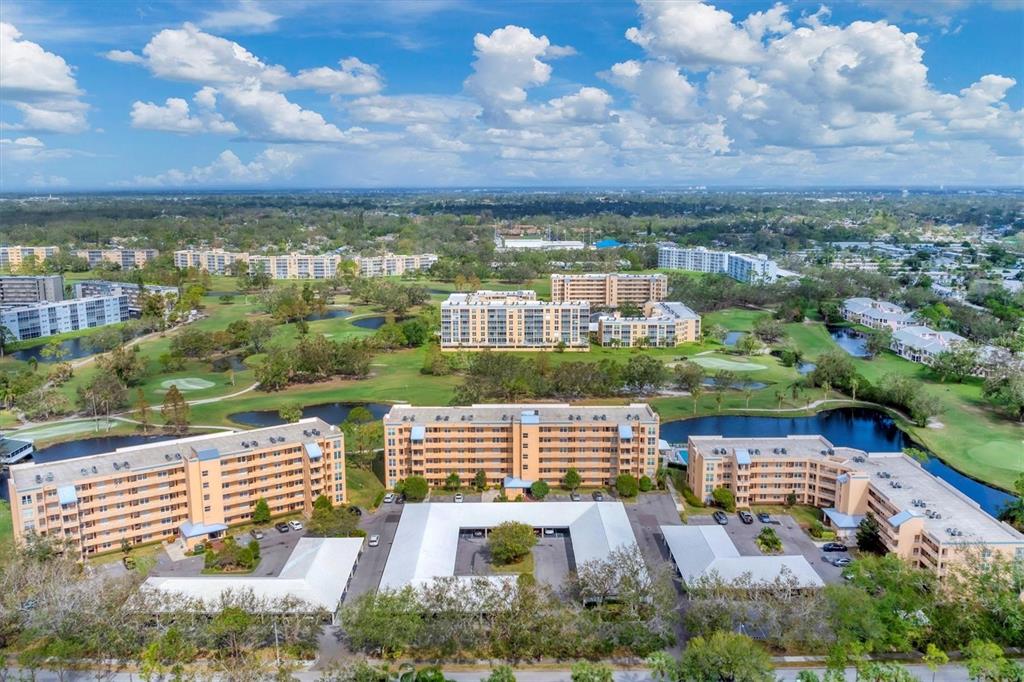 An aerial view shows several multi-story apartment buildings surrounded by a golf course and ponds — 4530 PINEBROOK CIRCLE UNIT 208, BRADENTON, FL
