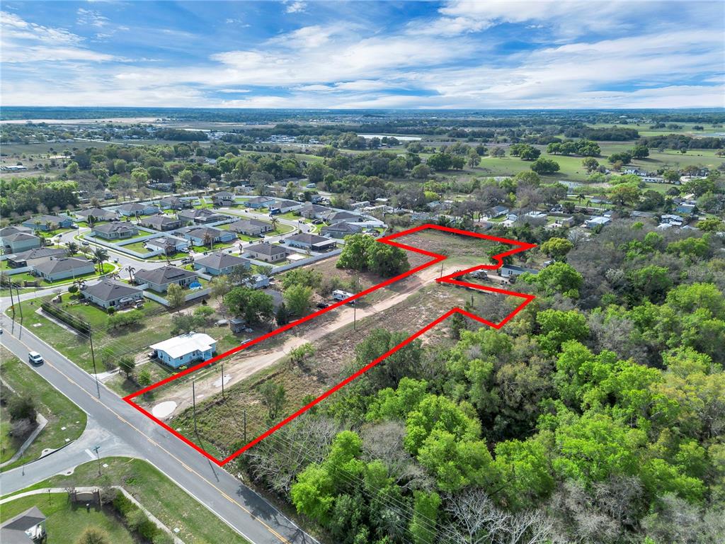 An aerial view shows a long, narrow vacant lot outlined in red next to a road — 701 MYSTERY HOUSE ROAD, DAVENPORT, FL