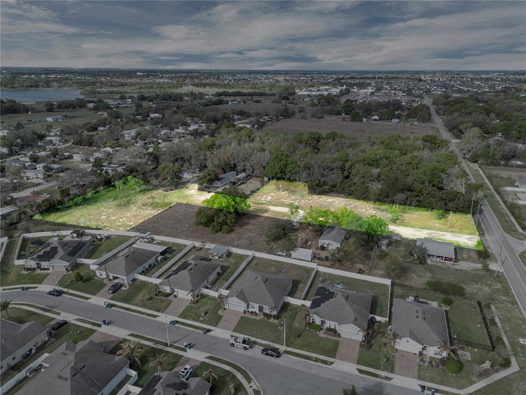 An aerial view shows a rectangular vacant lot highlighted in green behind a suburban neighborhood — 701 MYSTERY HOUSE ROAD, DAVENPORT, FL