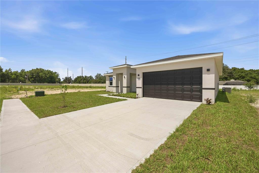 A modern single-story house with a concrete driveway and a dark two-car garage — 2122 RIVER HAWK LOOP, WINTER HAVEN, FL