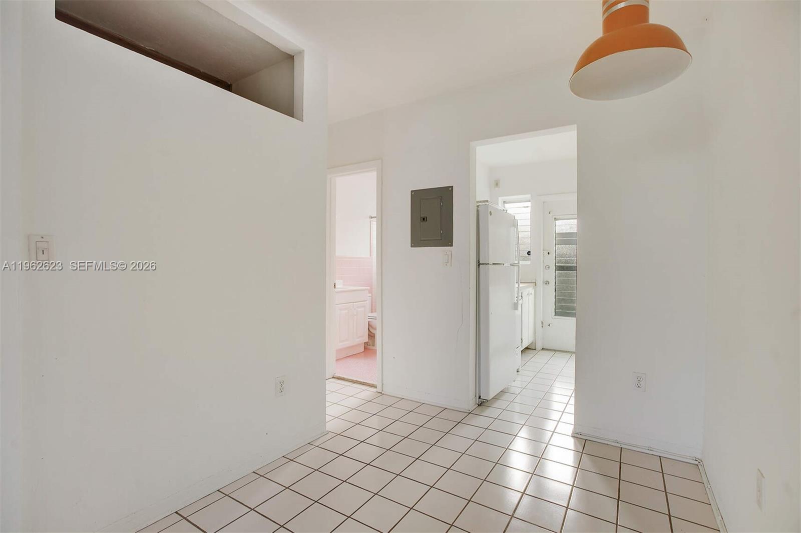A white-walled room with tiled floors features a doorway to a bathroom and kitchen — 835 Meridian Ave # 3, Miami Beach FL 33139, MIAMI BEACH, FL