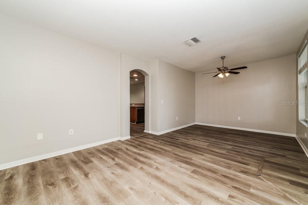 An empty living room with light-colored walls, wood-look flooring, and a ceiling fan — 1516 BLUE MAGNOLIA ROAD, BRANDON, FL