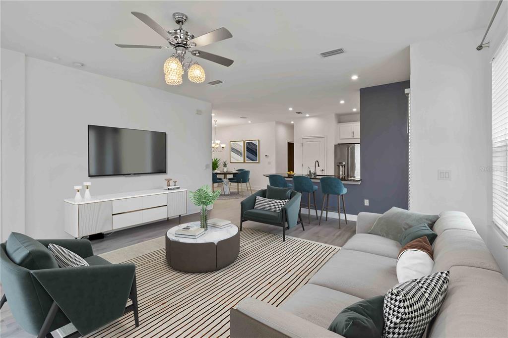 A modern living room features a large sectional sofa, two armchairs, and an open kitchen — 10934 WENDOVER DRIVE, PALMETTO, FL