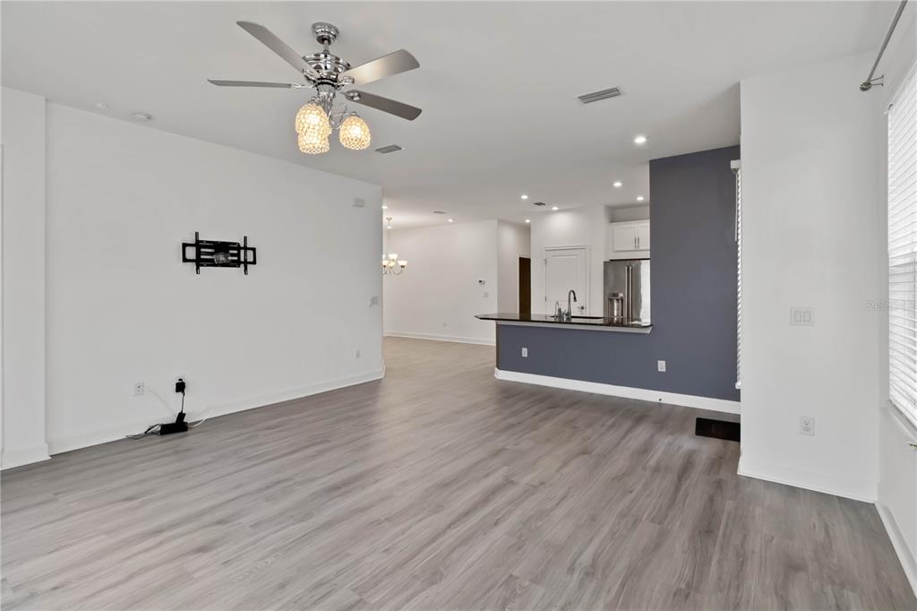 An open-concept living area features light wood-look flooring, a ceiling fan, and a kitchen island — 10934 WENDOVER DRIVE, PALMETTO, FL