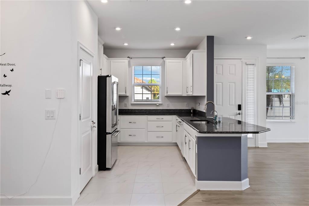 A kitchen with white cabinets, dark granite countertops, stainless steel appliances, and tile flooring — 10934 WENDOVER DRIVE, PALMETTO, FL