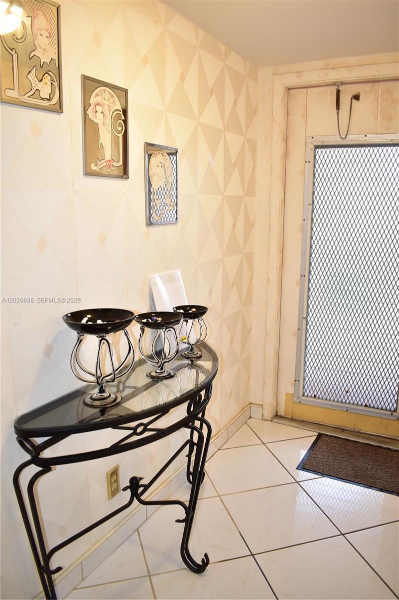 A glass-topped console table with three decorative bowls stands in an entryway with tiled floors — 9461 Sunrise Lakes Blvd # 103, Sunrise FL 33322, SUNRISE, FL