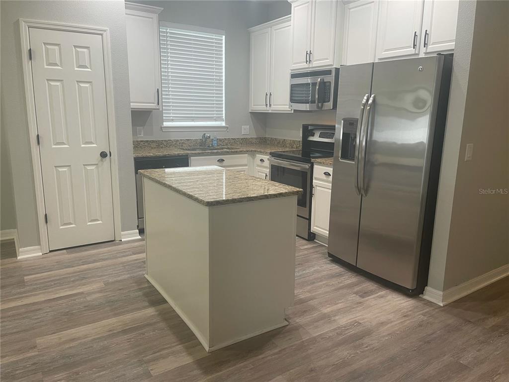 A kitchen features white cabinets, granite countertops, stainless steel appliances, and a central island — 30823 SATINLEAF RUN, BROOKSVILLE, FL