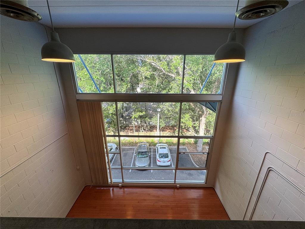 A high-angle view of a room with white block walls, hardwood floors, and large windows — 2515 SW 35TH PLACE UNIT 209, GAINESVILLE, FL