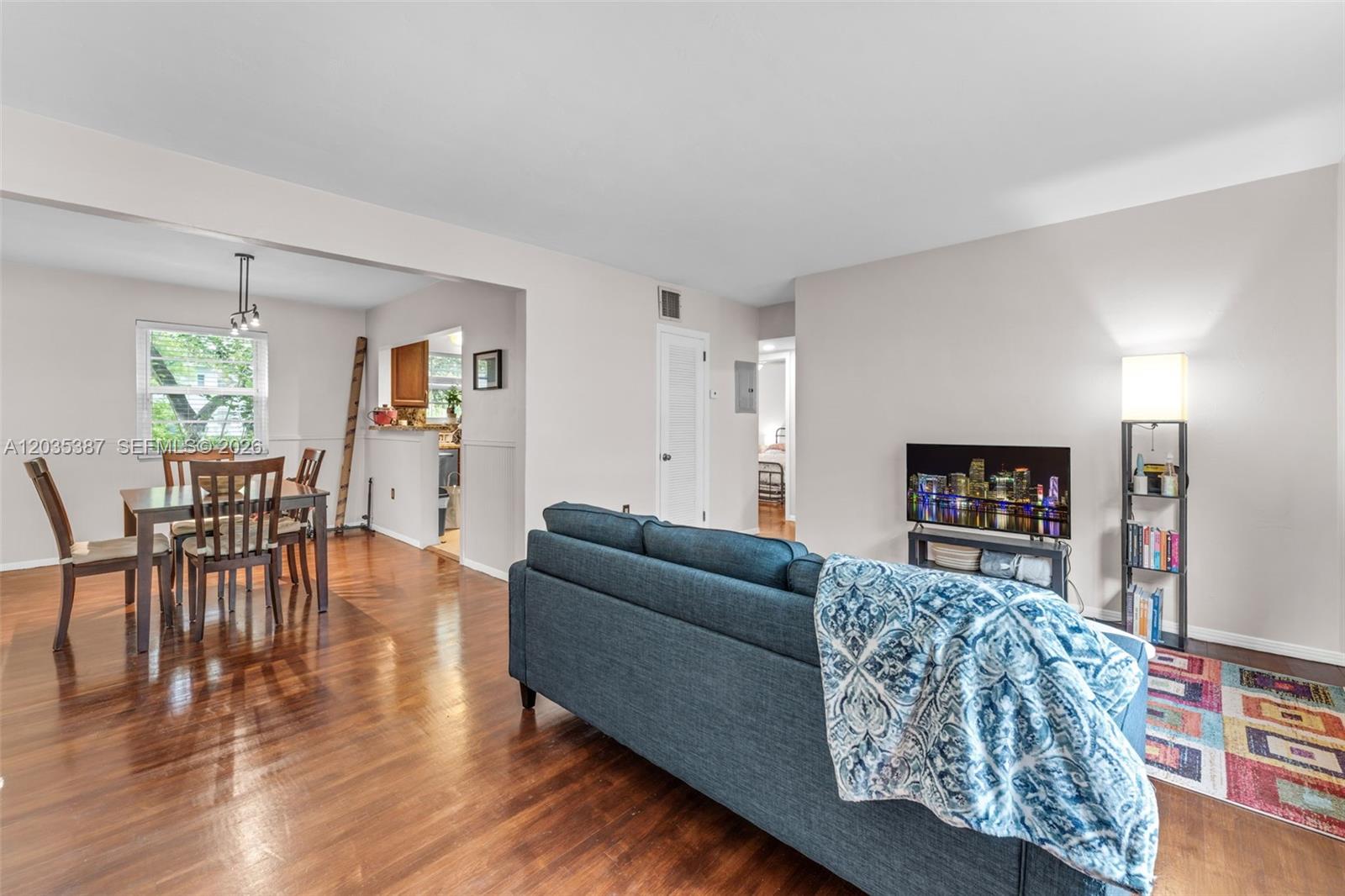 A living room and dining area feature hardwood floors, a blue sofa, and a television — 5685 SW 80th St # 58B, Miami FL 33143, MIAMI, FL