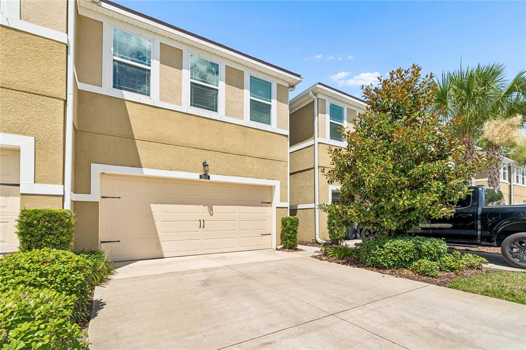 A two-story tan townhouse with a two-car garage and a concrete driveway — 17852 ALTHEA BLUE PLACE, LUTZ, FL