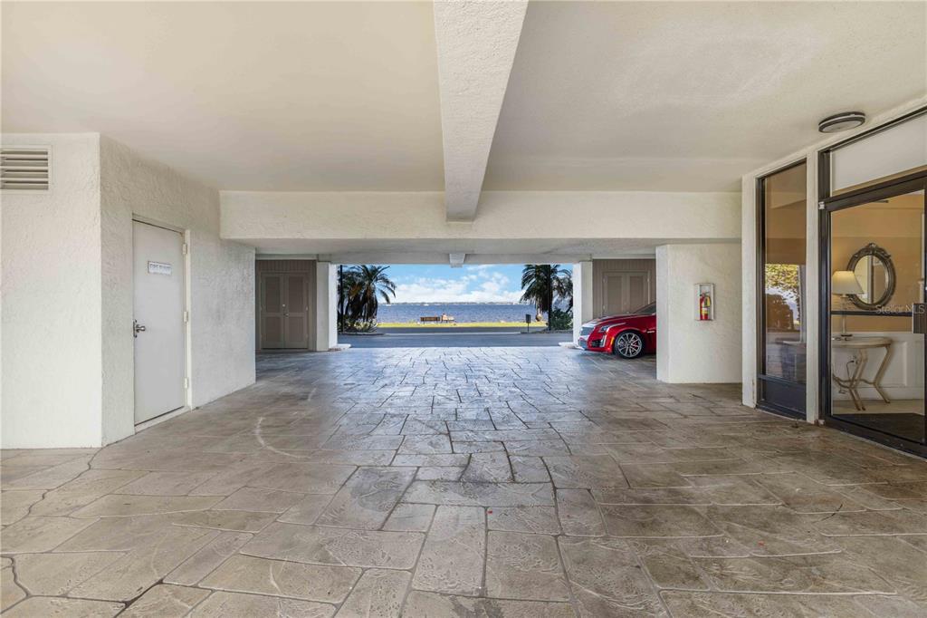 A covered parking area with stone flooring leads to a view of the water — 1500 PARK BEACH CIRCLE UNIT 6C, PUNTA GORDA, FL