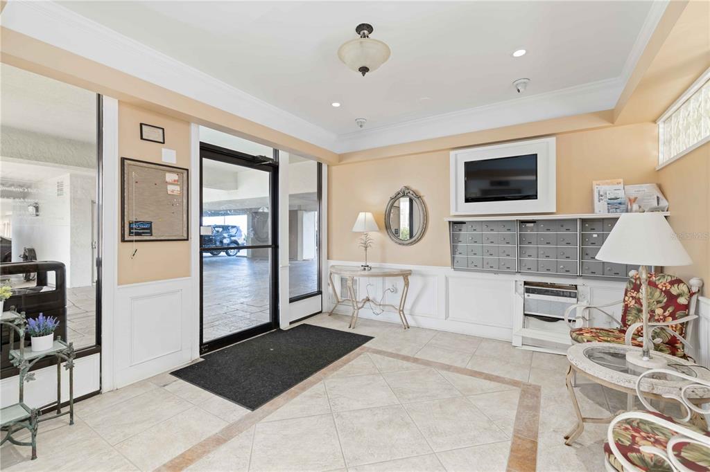 A lobby features tile flooring, a wall of mailboxes, a television, and a glass door — 1500 PARK BEACH CIRCLE UNIT 6C, PUNTA GORDA, FL