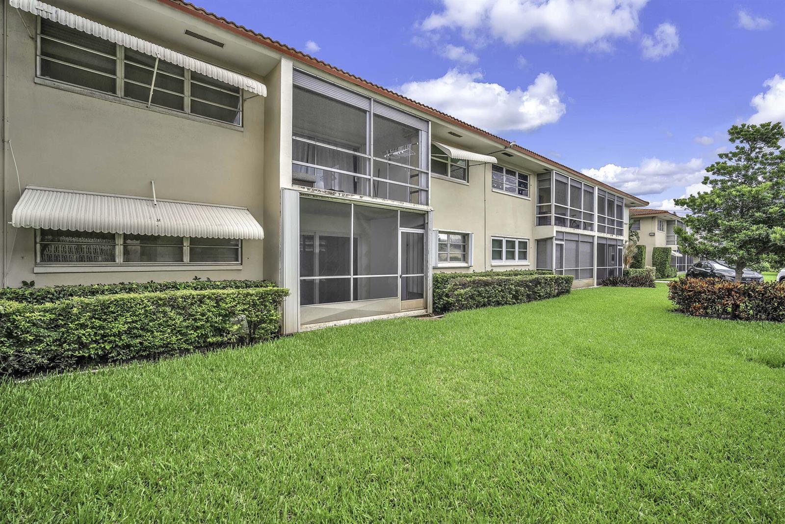 The exterior of a two-story apartment building features screened-in balconies and metal window awnings — 2130 NE 36th Street # 63, Lighthouse Point FL 33064, LIGHTHOUSE POINT, FL