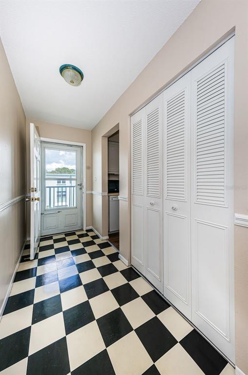 A hallway with a black and white checkered floor, louvered closet doors, and an exterior door — 1706 BELLEAIR FOREST DRIVE UNIT 322, BELLEAIR, FL