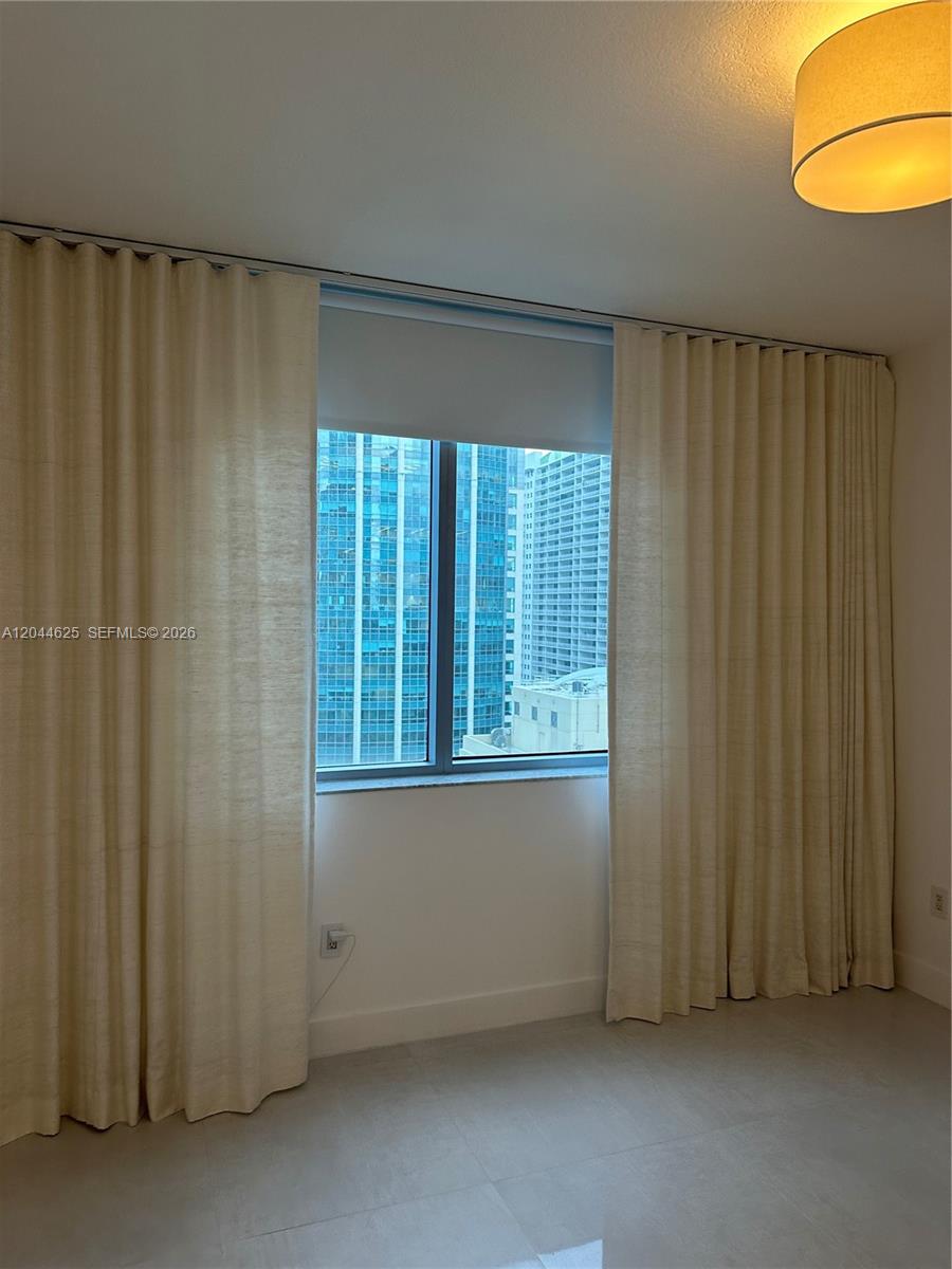A room features floor-to-ceiling curtains flanking a window overlooking a dense urban cityscape — 1060 Brickell Ave # 2505, Miami FL 33131, MIAMI, FL