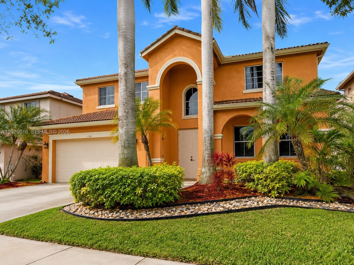 A two-story orange stucco house features a tiled roof, arched entryway, and palm trees — 1319 Croton Ct, Weston FL 33327, WESTON, FL