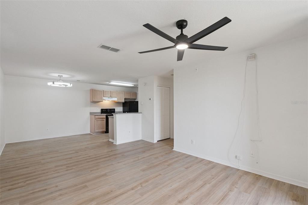 An open-concept living and dining area features light wood-look flooring and a black ceiling fan — 8813 LATREC AVENUE UNIT 206, ORLANDO, FL