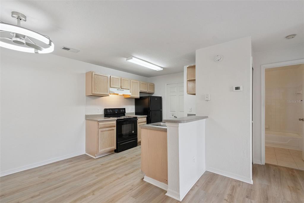 A kitchen with light wood cabinets, black appliances, and a breakfast bar — 8813 LATREC AVENUE UNIT 206, ORLANDO, FL
