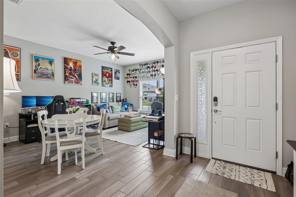 A view from an entryway into a living room and dining area with wood-look flooring — 8210 MALLOW MIRROR LANE, LAND O LAKES, FL