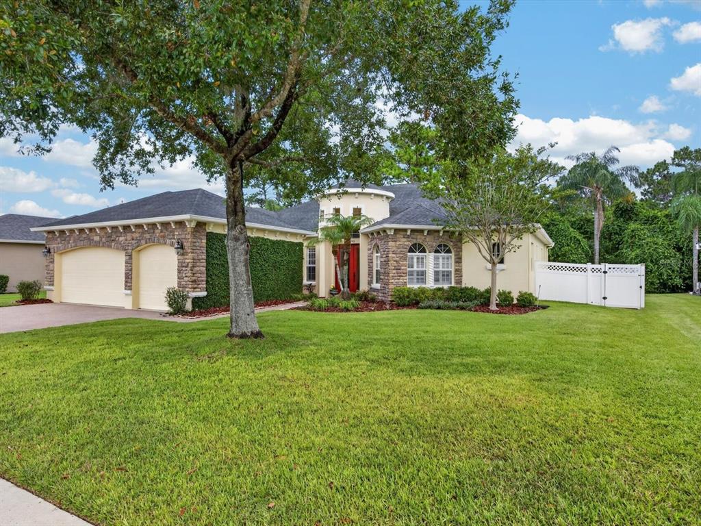 A single-story house with a stone facade, a two-car garage, and a large front lawn — 3692 HEIRLOOM ROSE PLACE, OVIEDO, FL
