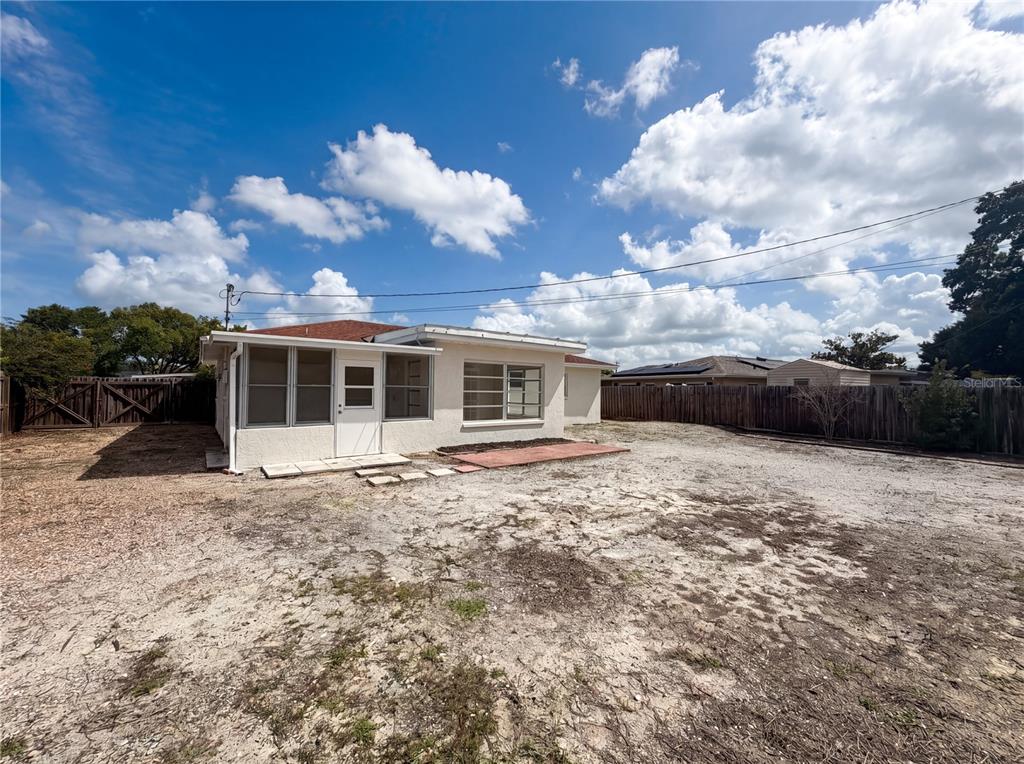 The exterior of a white house with a screened-in porch and a large dirt yard — 7328 TANGELO AVENUE, PORT RICHEY, FL