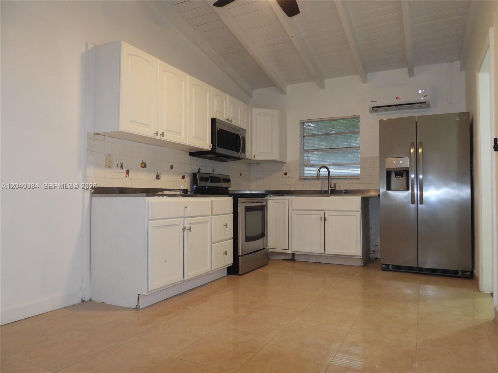 A kitchen features white cabinets, stainless steel appliances, a tiled backsplash, and light-colored floor tiles — MIAMI, FL