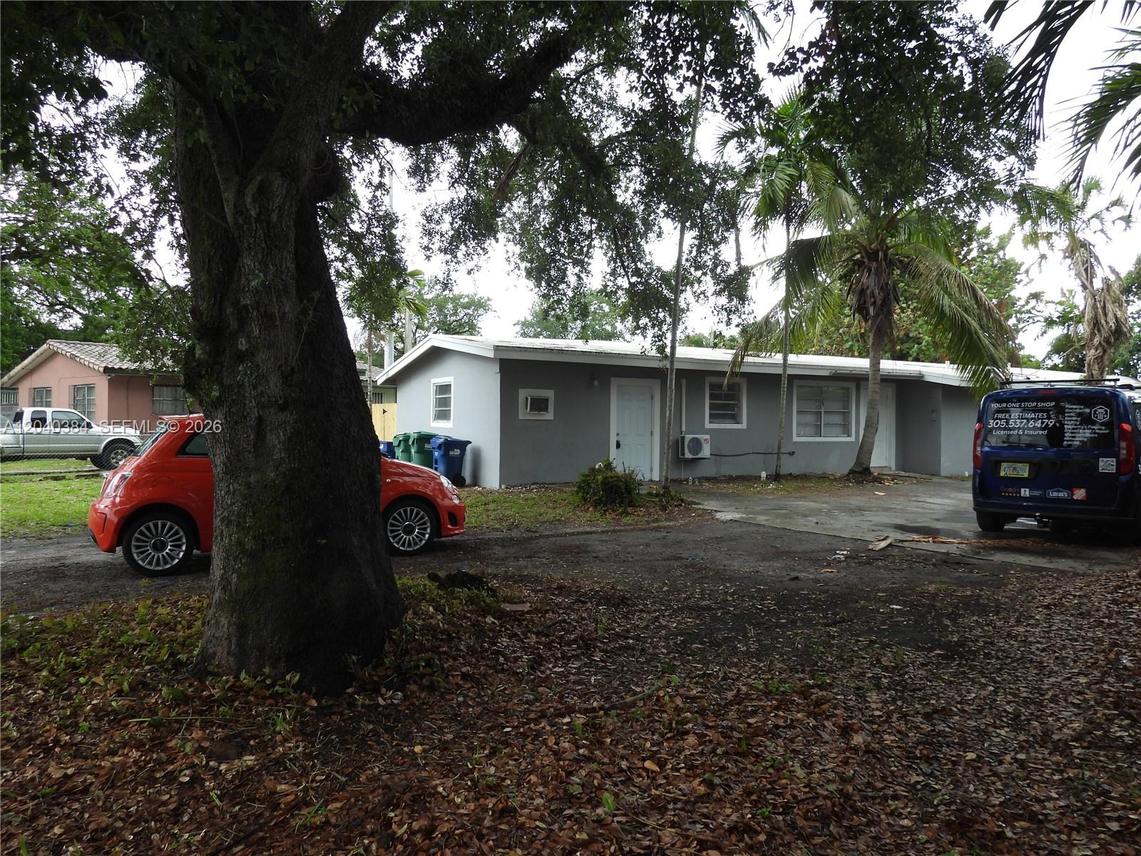 A gray single-story house with a large tree in the front yard — MIAMI, FL