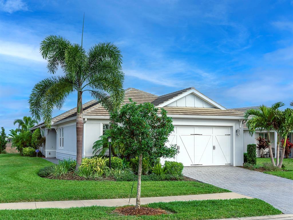 A single-story house with a white garage, palm trees, and a green lawn — 1010 CROSSWIND AVENUE, SARASOTA, FL