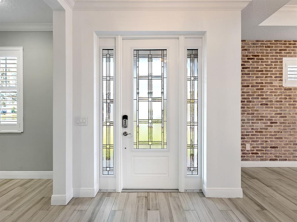 A white front door with decorative glass panels is flanked by sidelights in a foyer — 1010 CROSSWIND AVENUE, SARASOTA, FL