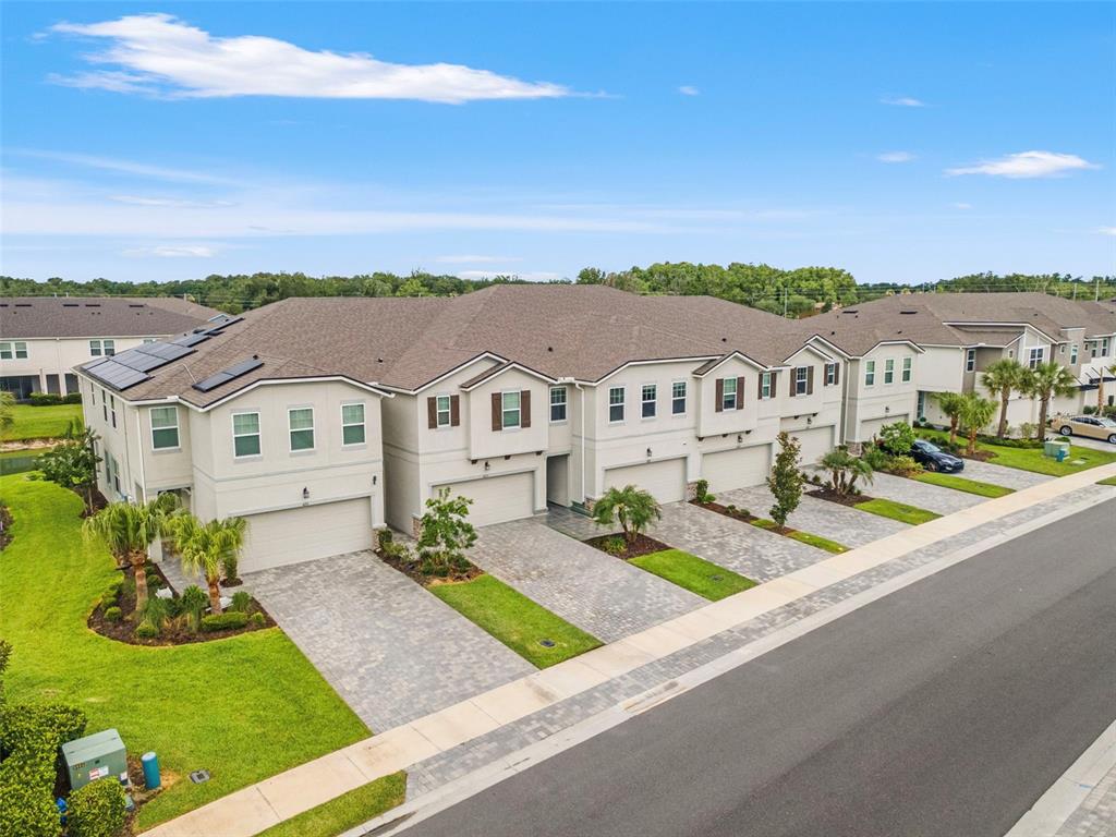 An aerial view of a row of multi-story townhomes with paved driveways and green lawns — 4221 CLOUD HOPPER WAY, LUTZ, FL
