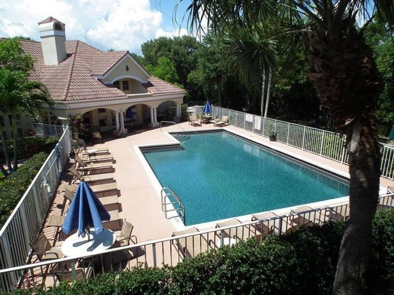 An outdoor swimming pool with lounge chairs and a covered patio area at a house — 815 W Boynton Beach Boulevard # 204, Boynton Beach FL 33426, BOYNTON BEACH, FL