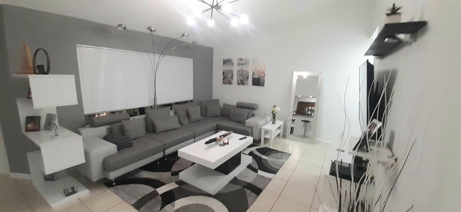 A modern living room features a gray sectional sofa, a white coffee table, and tiled floors — 815 W Boynton Beach Boulevard # 204, Boynton Beach FL 33426, BOYNTON BEACH, FL