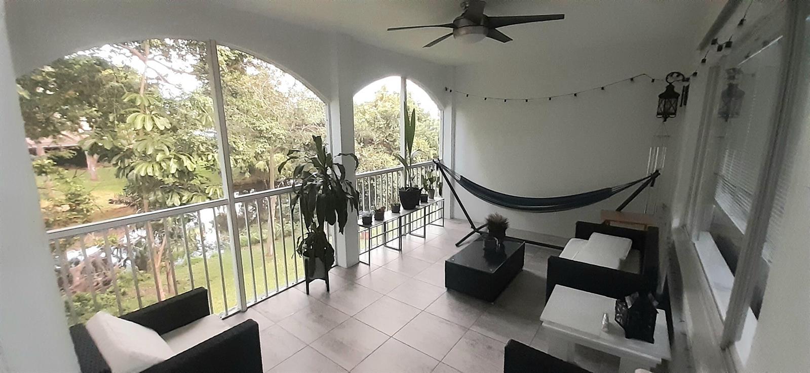 A screened-in balcony features tiled flooring, a hammock, patio furniture, and views of trees — 815 W Boynton Beach Boulevard # 204, Boynton Beach FL 33426, BOYNTON BEACH, FL